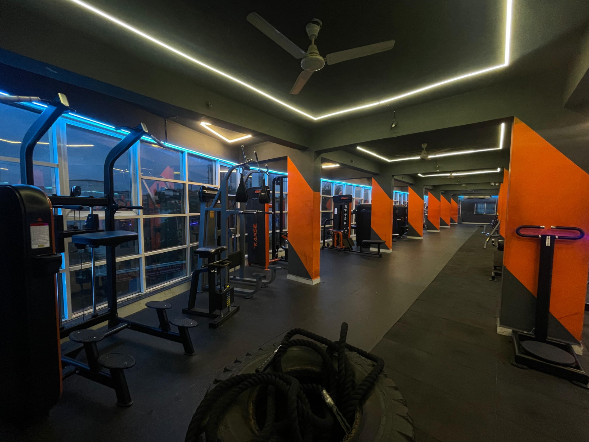 Long row of pin-loaded weight machines along the windowed wall at SK Fitness Gym, Kharadi Road, Pune Long row of pin-loaded weight machines along the windowed wall at SK Fitness Gym, Kharadi Road, Pune